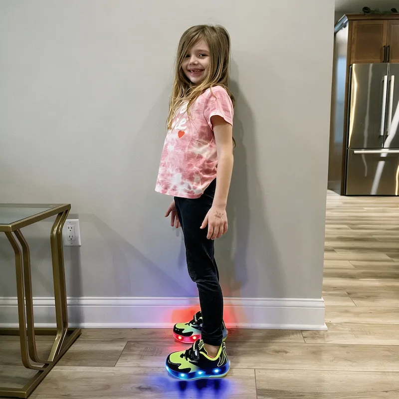 Little girl wearing colorful LED light‑up wheeled shoes at home interior